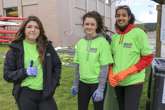 Students wearing green shirts at a waste sorting station