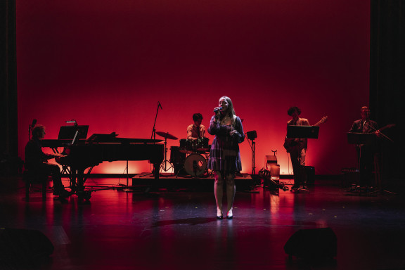 A private school student performs on stage with a band