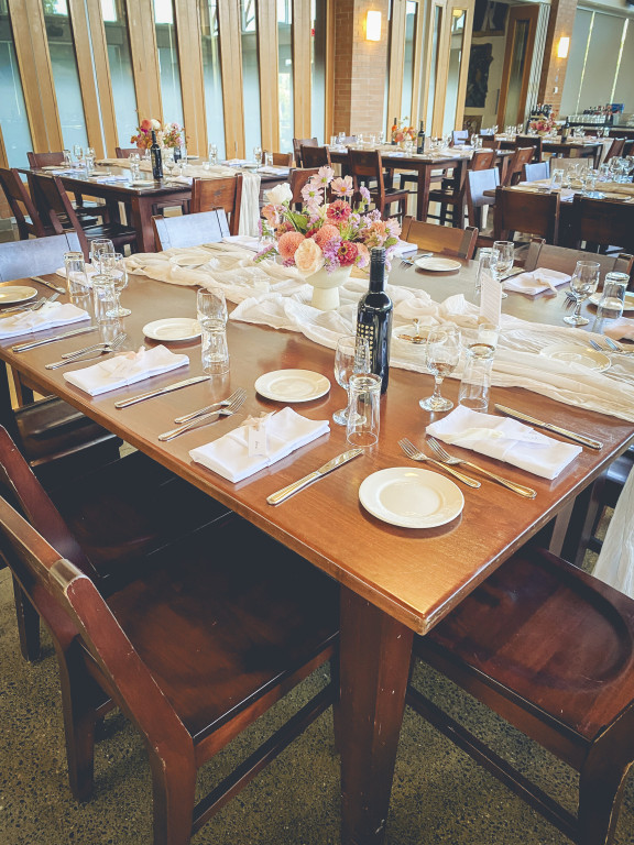 Tables set with linen, glassware, wine, and fresh flowers for special event