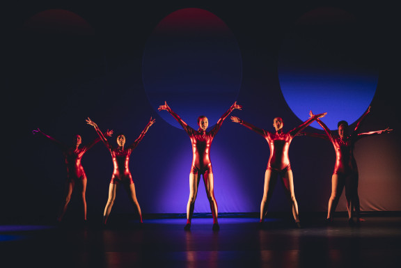 A group of dancers on stage with their hands in the air