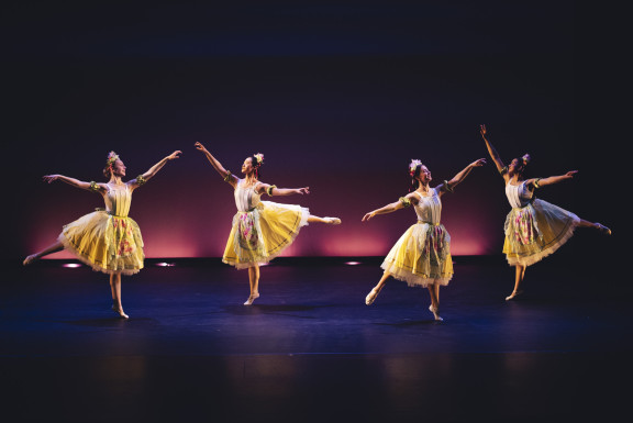 Four ballerinas in yellow dresses dancing