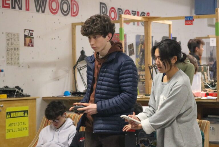 Male and female Robotics students concentrate on operating their creations