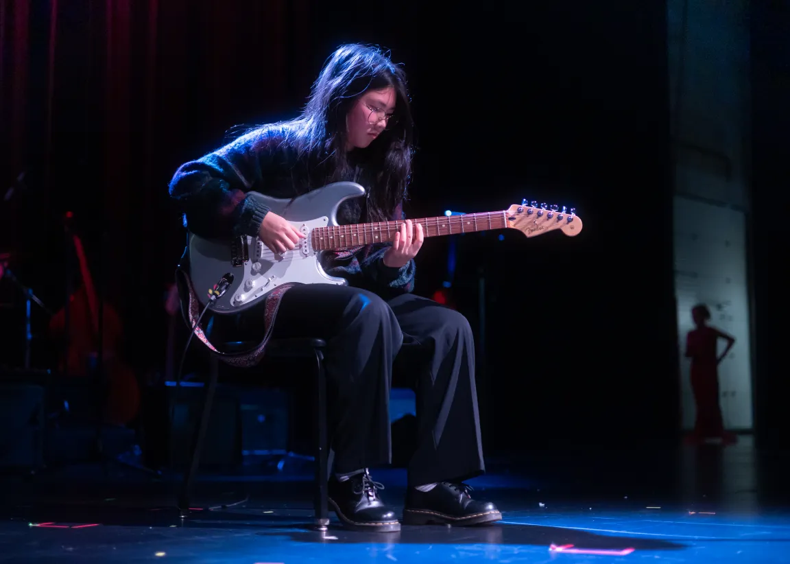 Boarding school student performing a guitar solo on stage