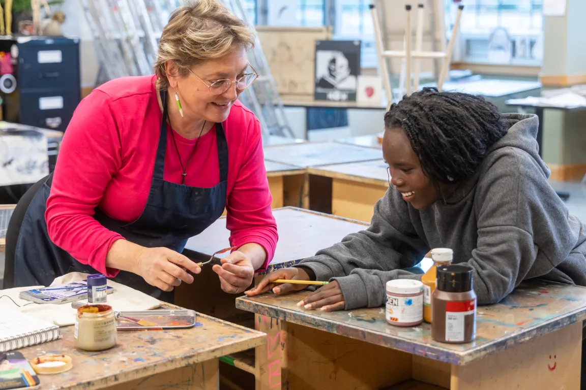Art teacher helping a student with a project in the studio
