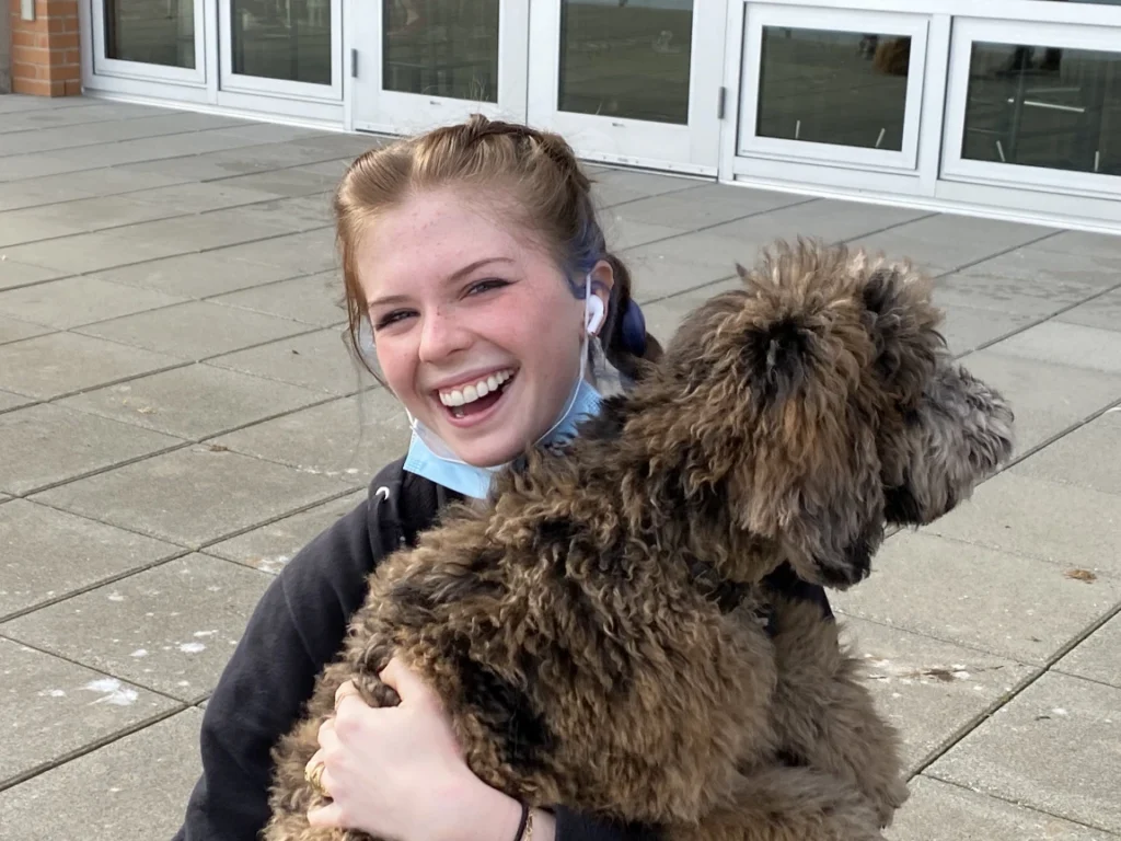 A student smiling while holding a therapy dog