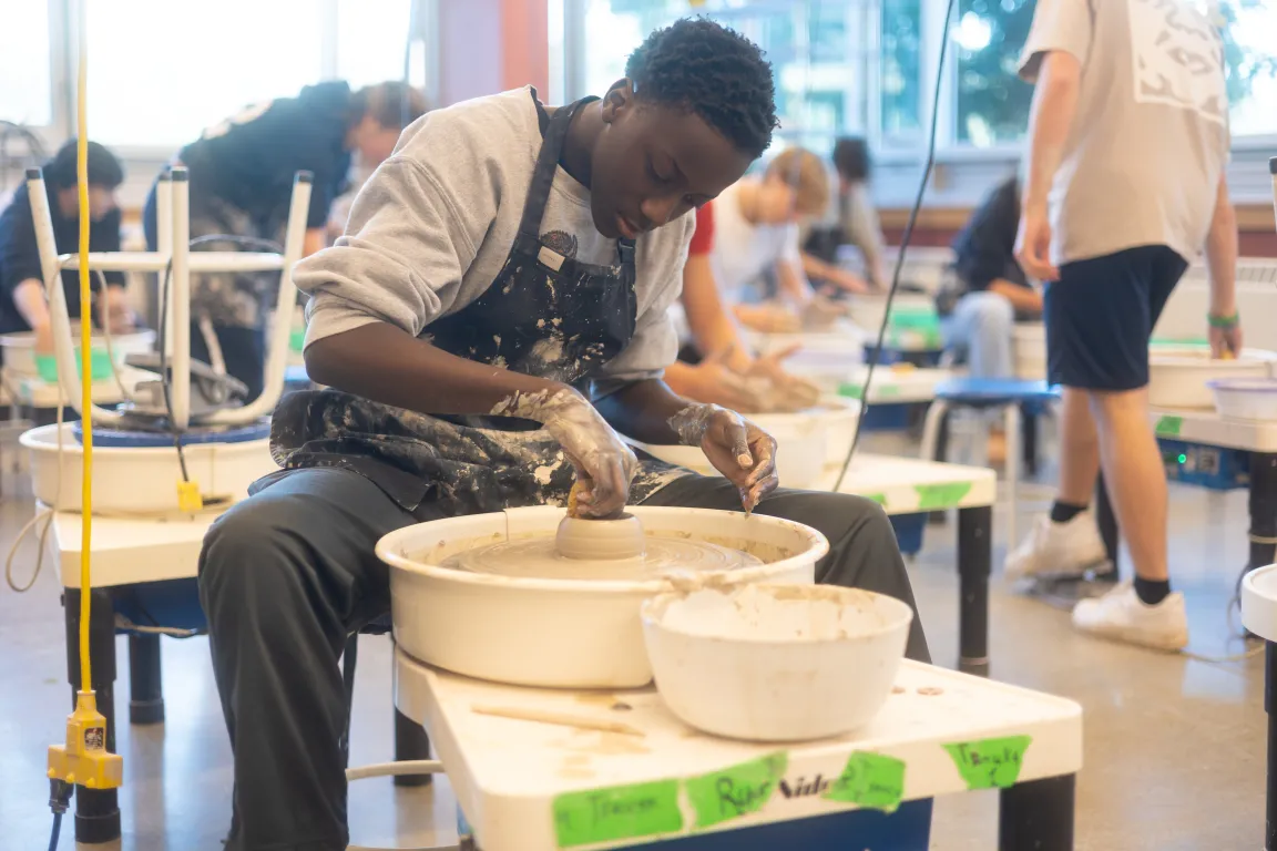 A ceramics student shaping a bowl at the pottery wheel