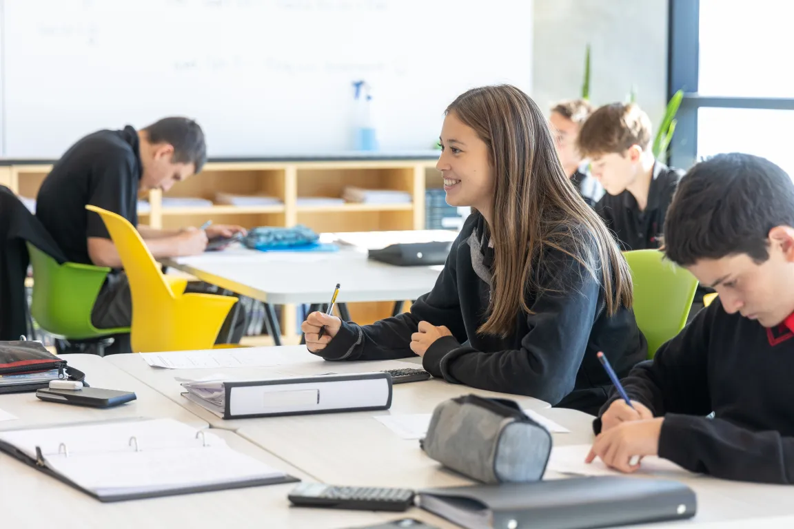 A student smiling during class in a bright, sunny classroom