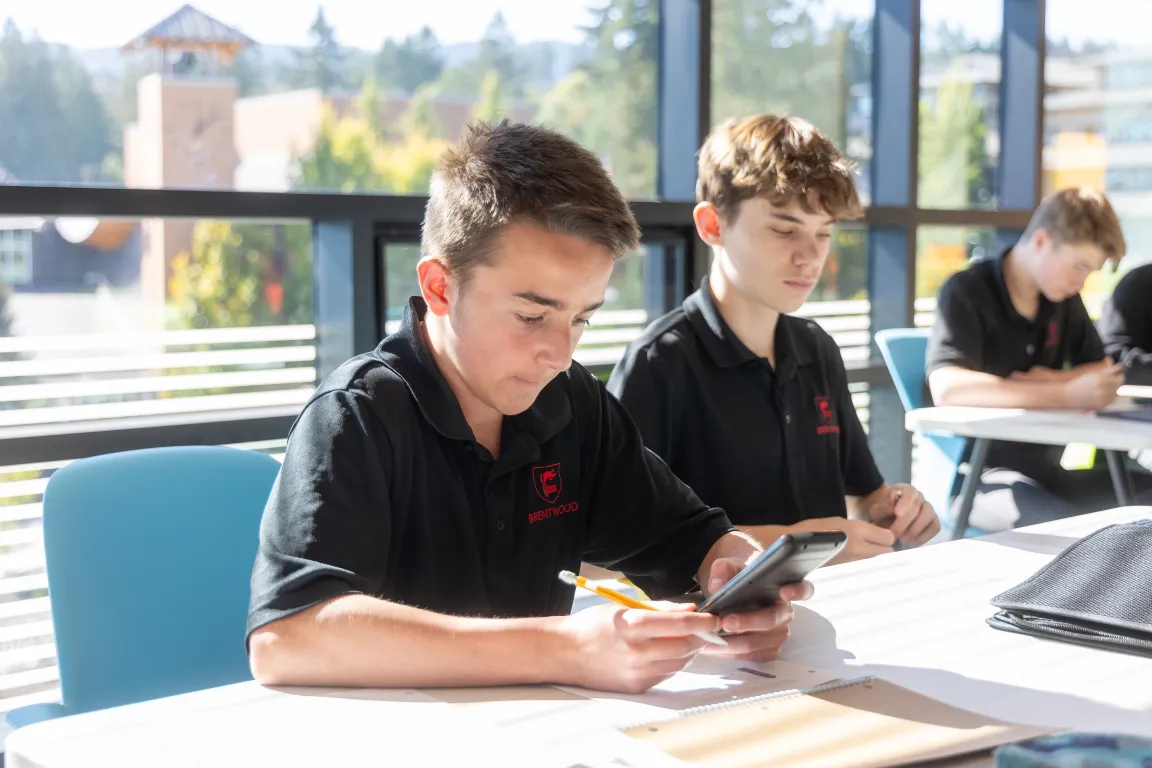 Boarding school students working with calculators in a sunny math classroom