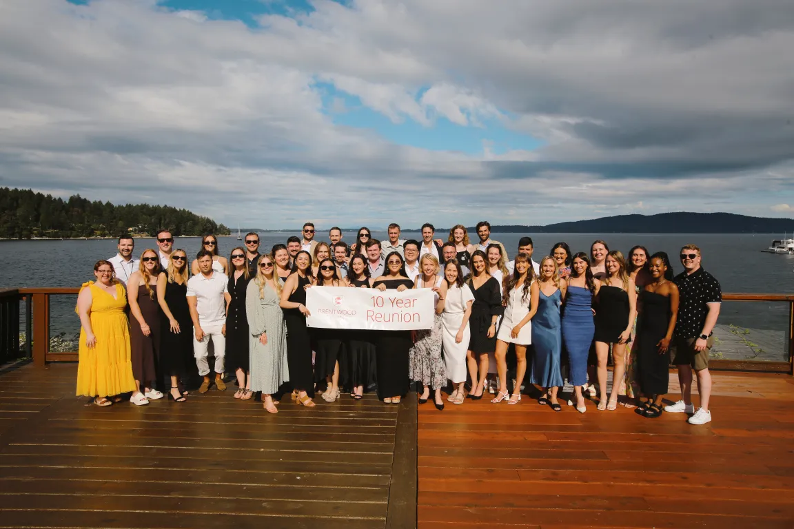 A large group of alumni posing with a banner at the 2024 Centenary reunion