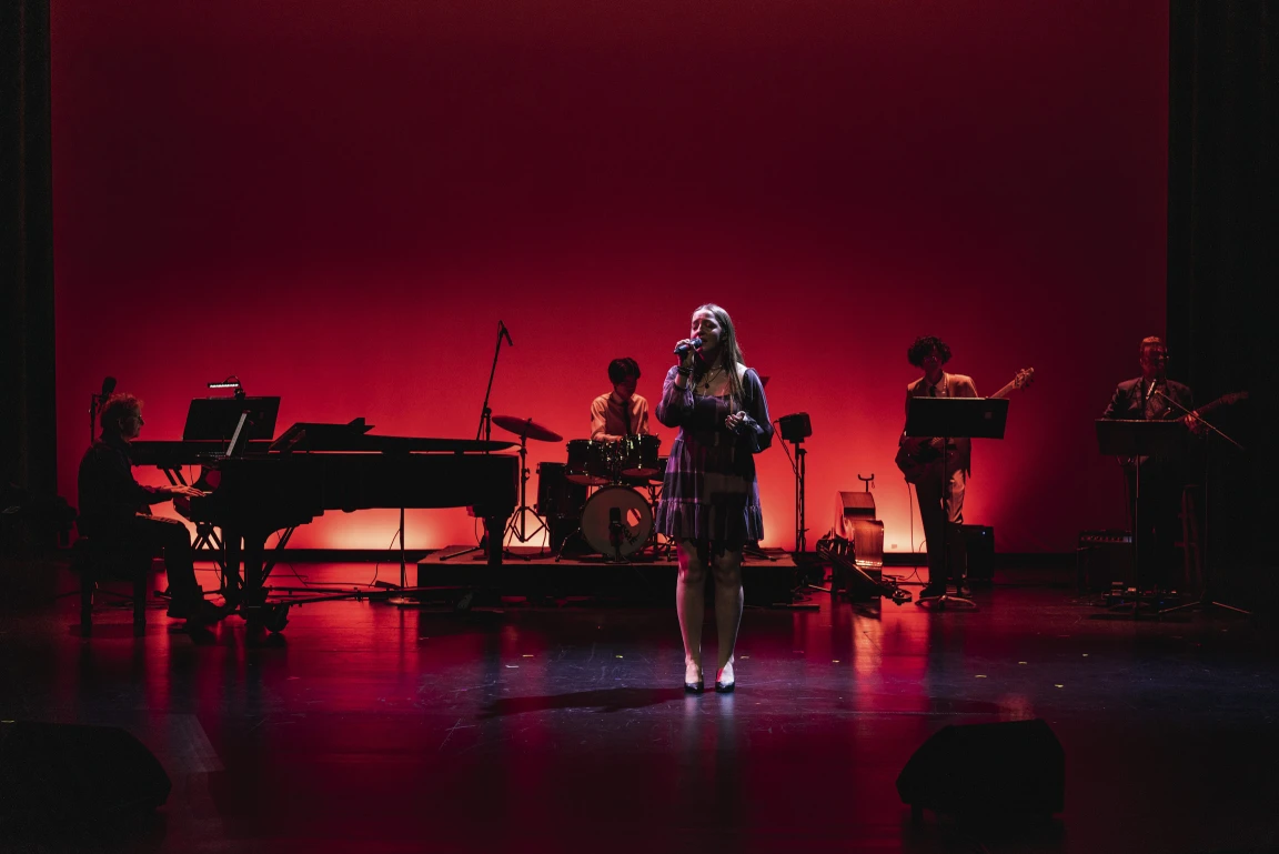 A private school student performs on stage with a band