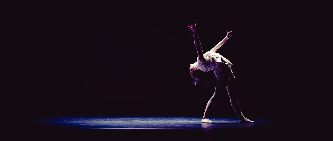 A dancer performing a solo under stage lighting