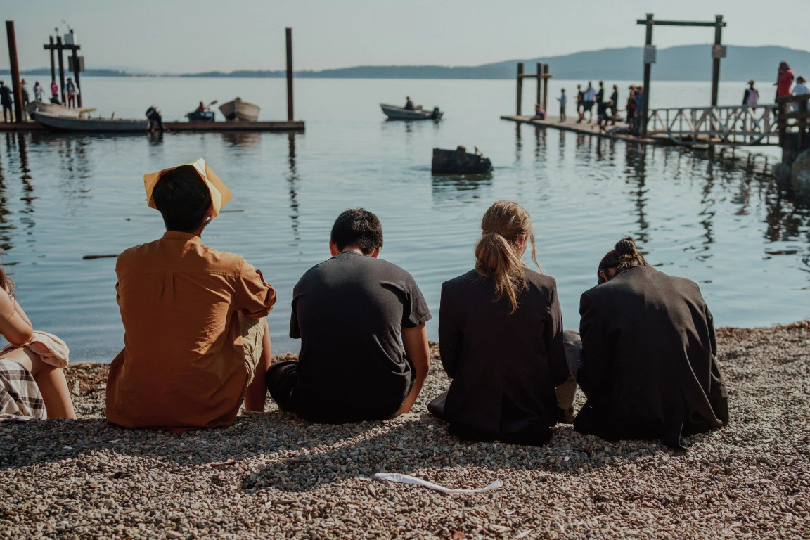 Students sitting together on the beach looking out at the water
