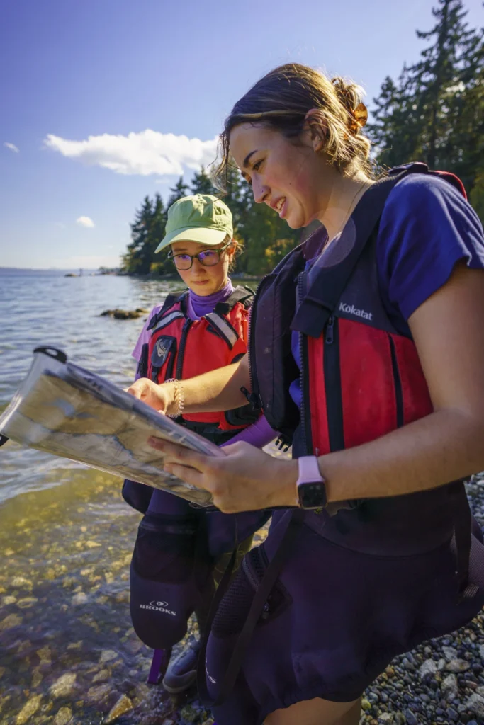 A student and teacher looking at sea charts