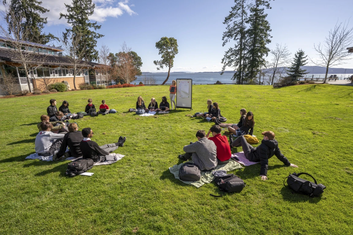 A private school academic language class siting outside with the ocean in the background