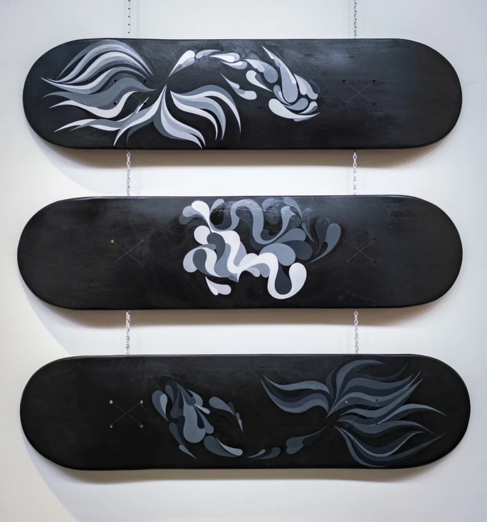 Three skateboards painted in black and grey
