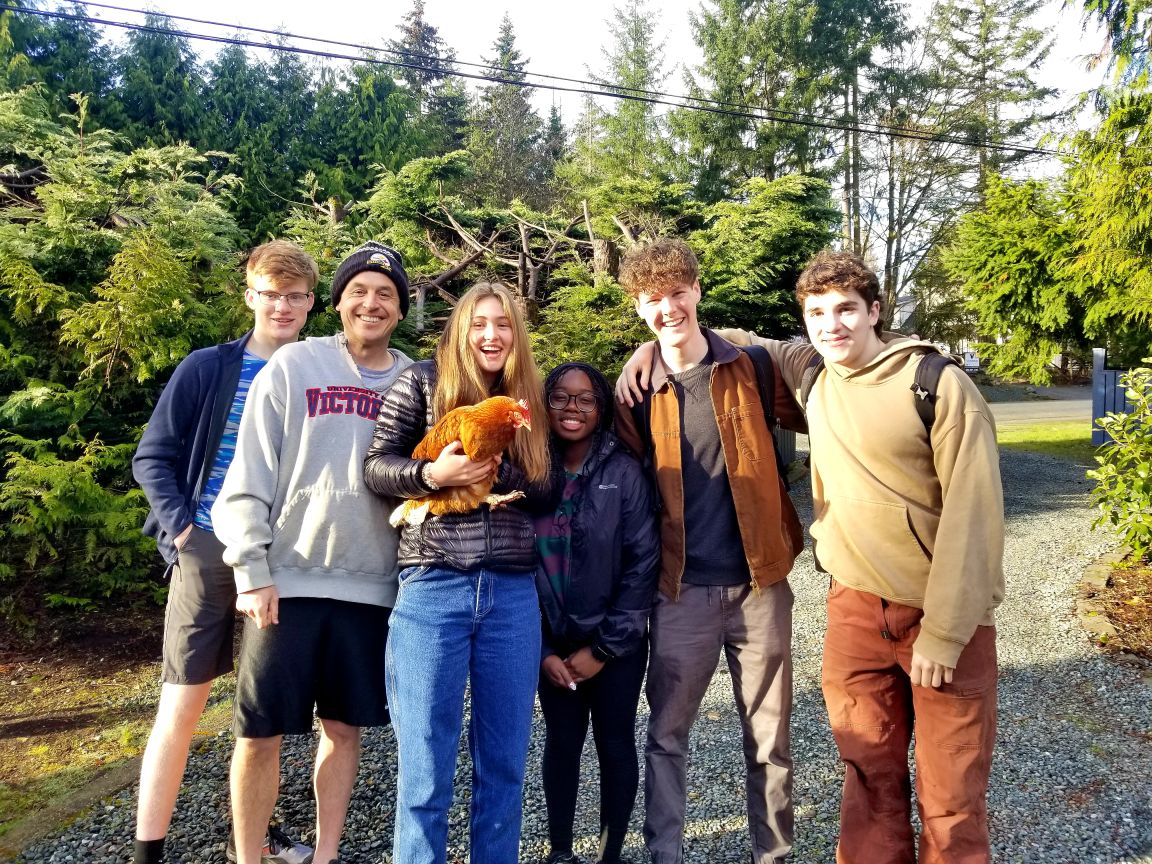 Students and teacher smiling as they pause their Service Day work