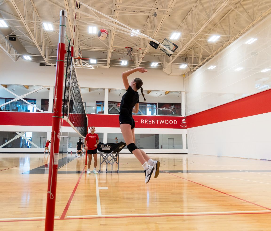 A student jumping to spike during volleyball in the Foote Centre gym