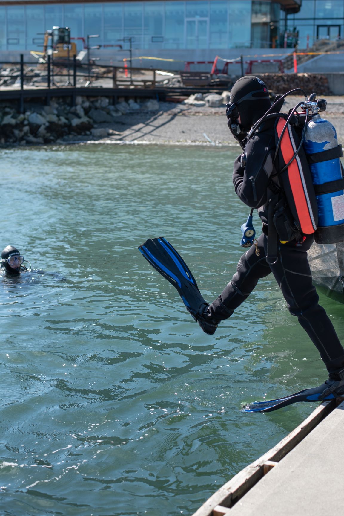 A student in scuba gear stepping off the dock into the water