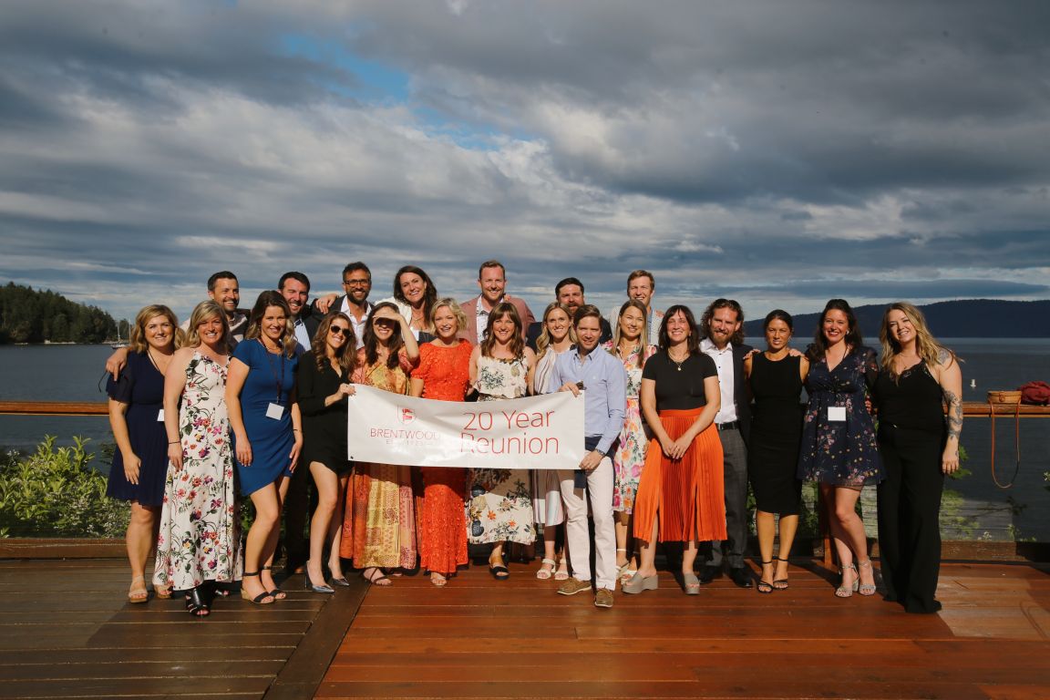 A large group of alumni posing with a reunion banner at the 2024 Centenary celebration