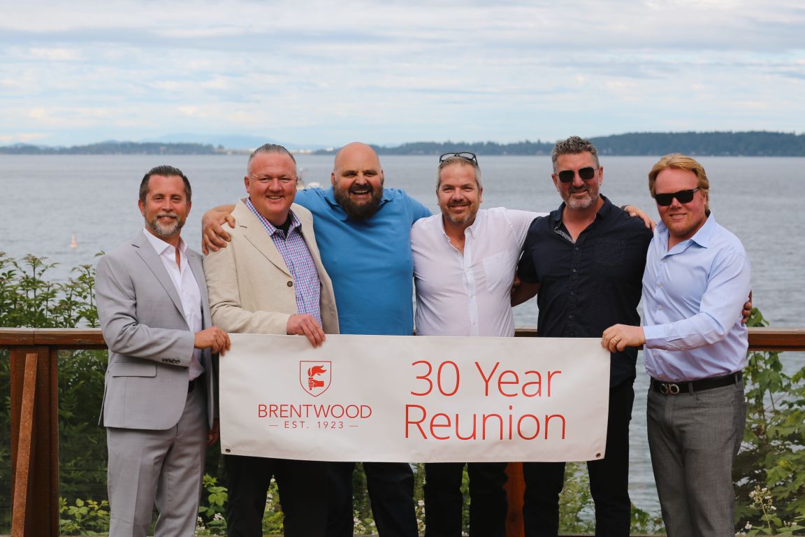 Alumni holding a 30 Year Reunion banner at the 2024 Centenary celebration