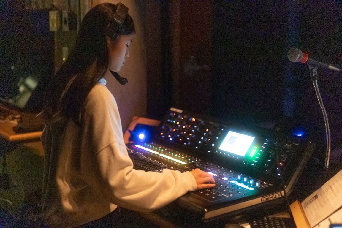 Boarding school student operating the audio mixing desk during a stage musical