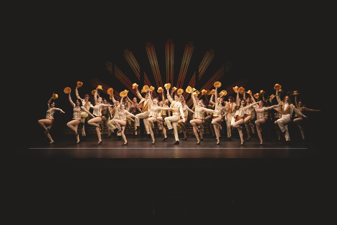 Students performing a large group dance number on stage