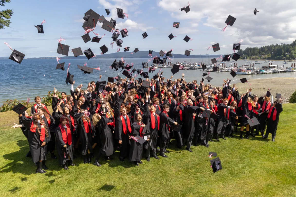 Graduating students tossing their caps in the air by the waterfront