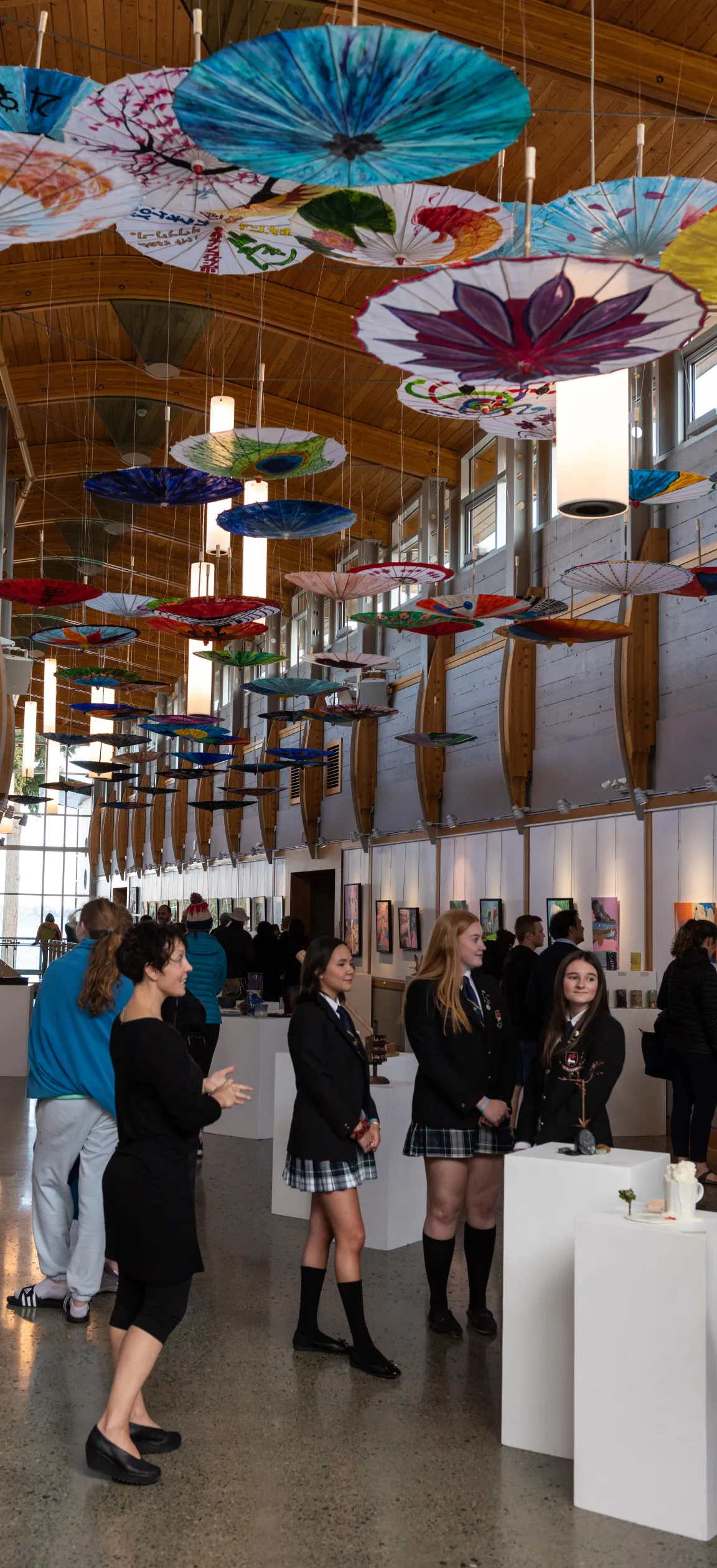 Students viewing painted umbrellas hanging in the art show at the regatta