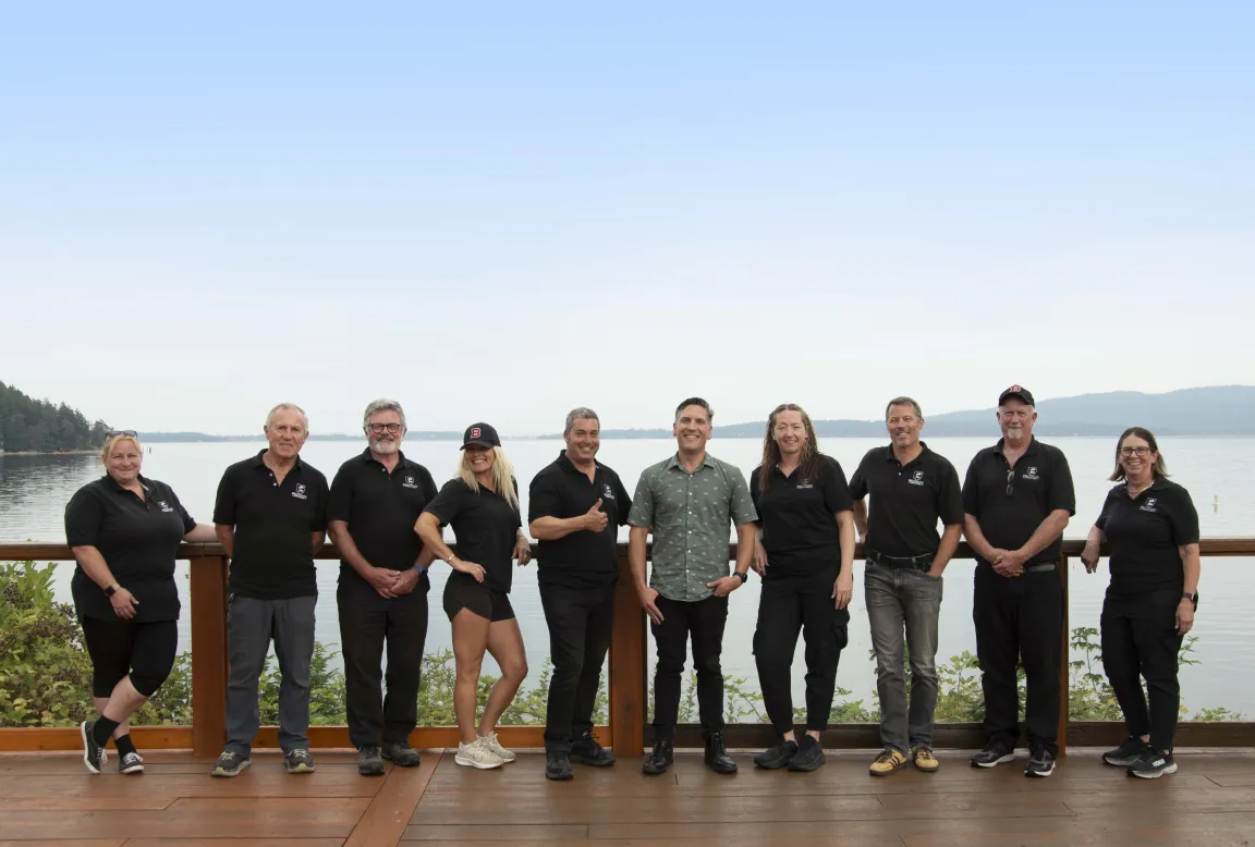 The Brentwood bus drivers standing together on a deck overlooking the water
