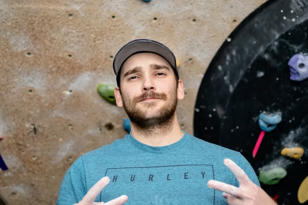 Tyler Ethier standing in front of the climbing wall