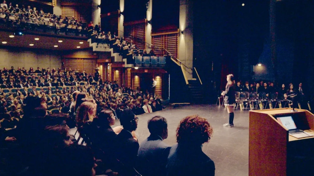 A packed theatre audience watching a performance on stage