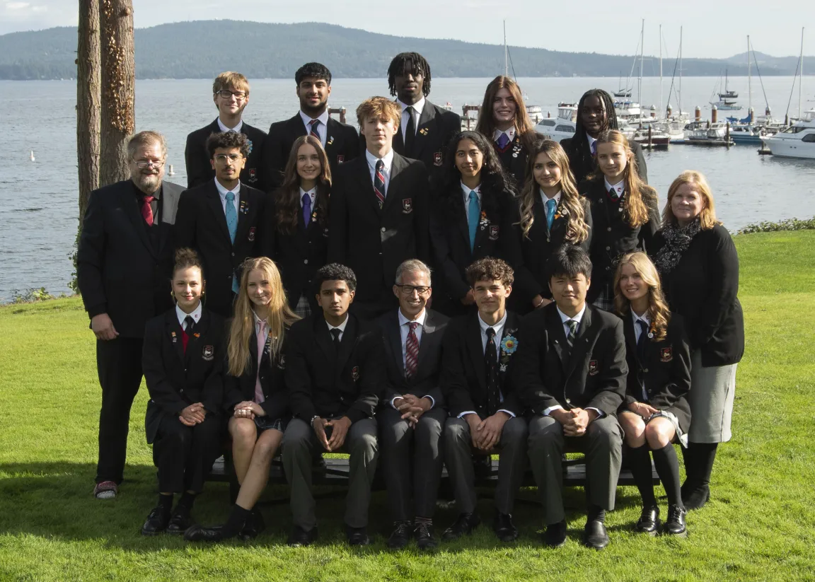 A group of students in school blazers posing together by the waterfront