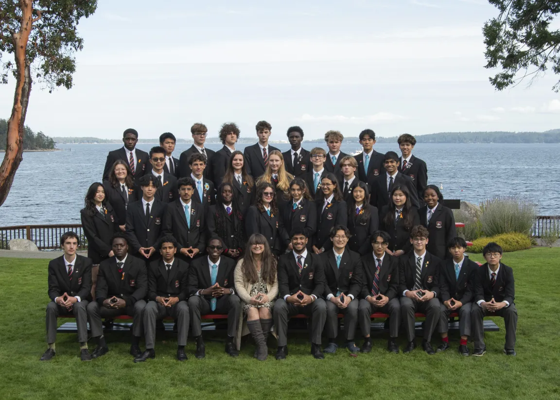 A large group of students in blazers posing together by the waterfront