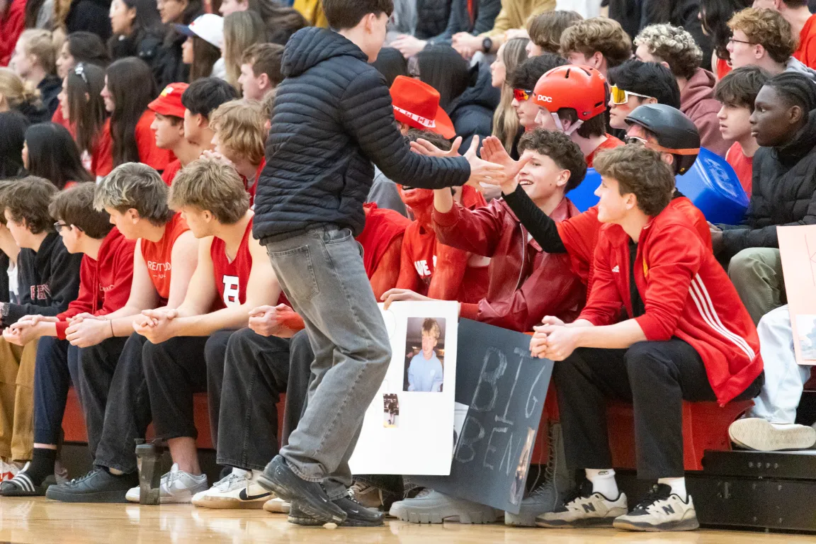 A student high-fiving classmates in the crowd at a school sports game