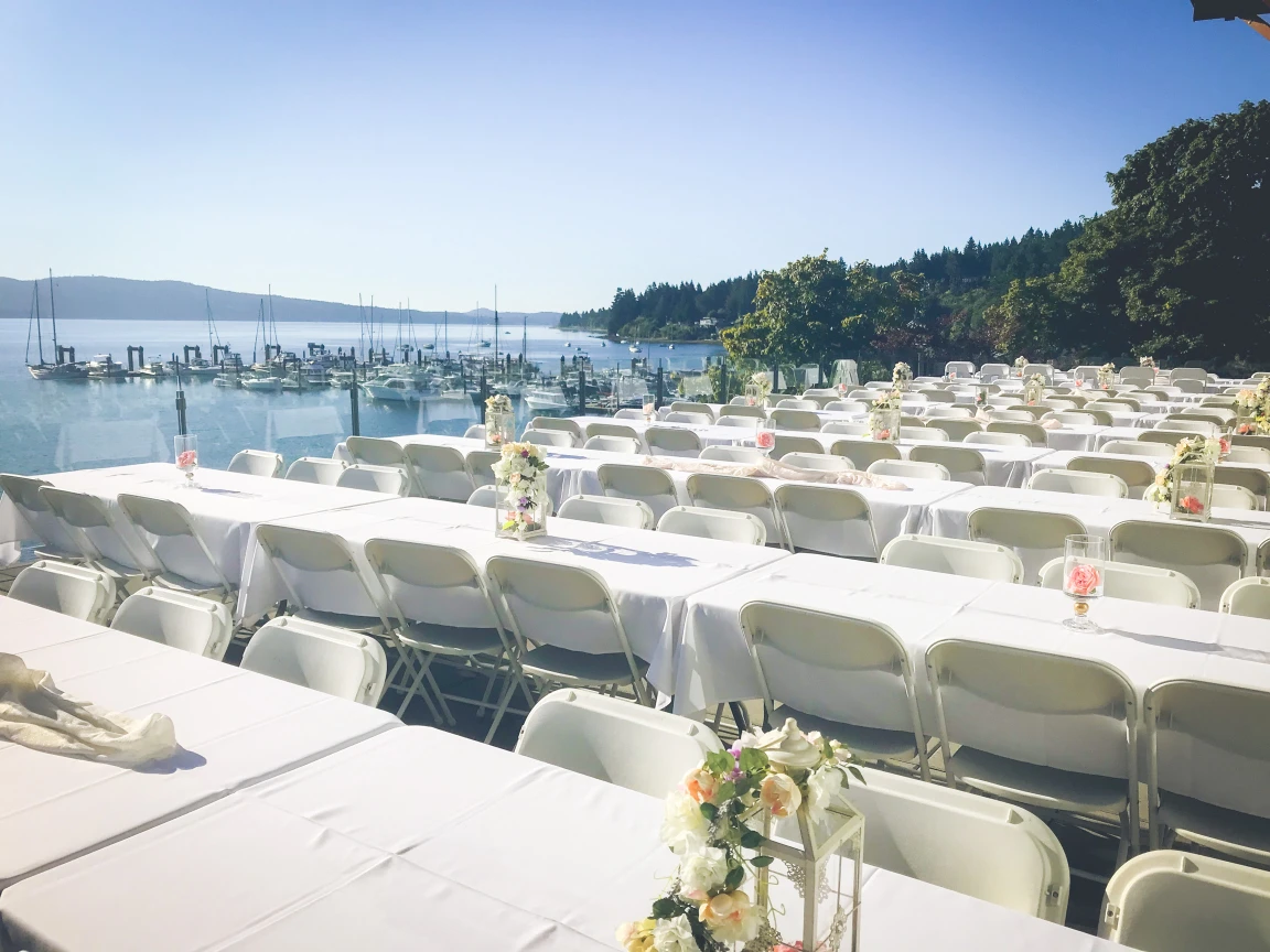 Crooks Hall balcony set with white linen long tables and fresh flowers, overlooking Mill Bay Marina and Saanich Inlet