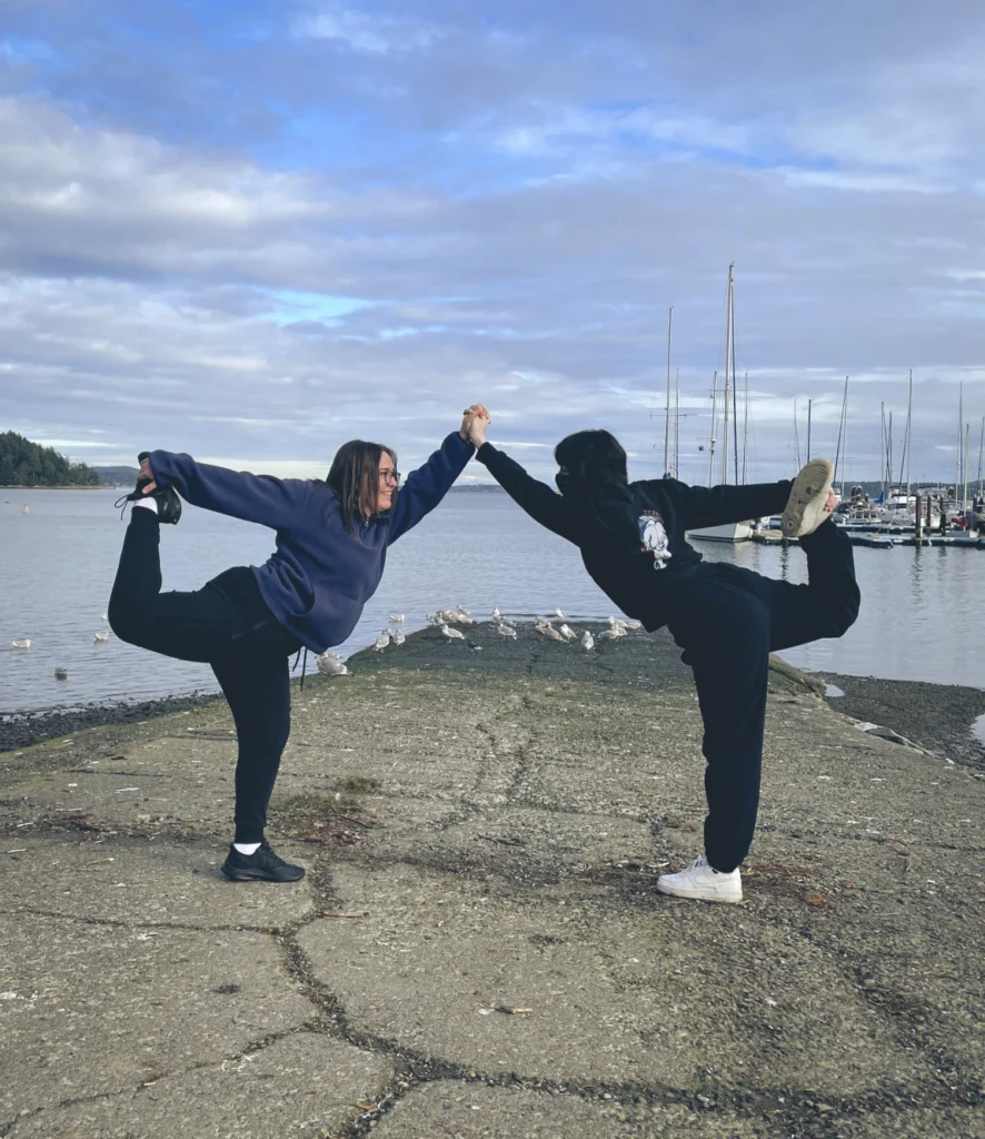 Two yoga students working together by the ocean